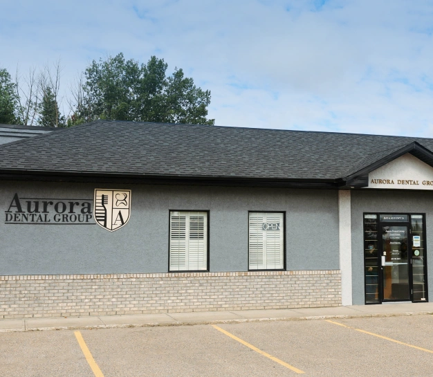 Exterior of the Aurora Dental Group office building with signage and entrance visible from the parking lot