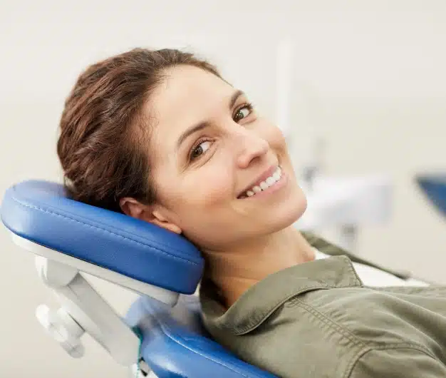 Smiling woman with brown hair relaxing in a blue dental chair during a comfortable visit