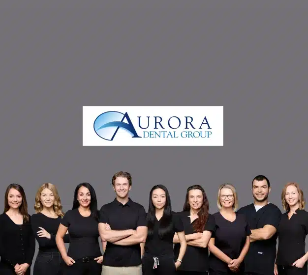 Aurora Dental Group logo above a team photo of nine staff members standing together in black attire