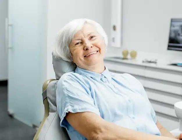 Smiling older woman with white hair relaxing in a dental chair during a comfortable visit