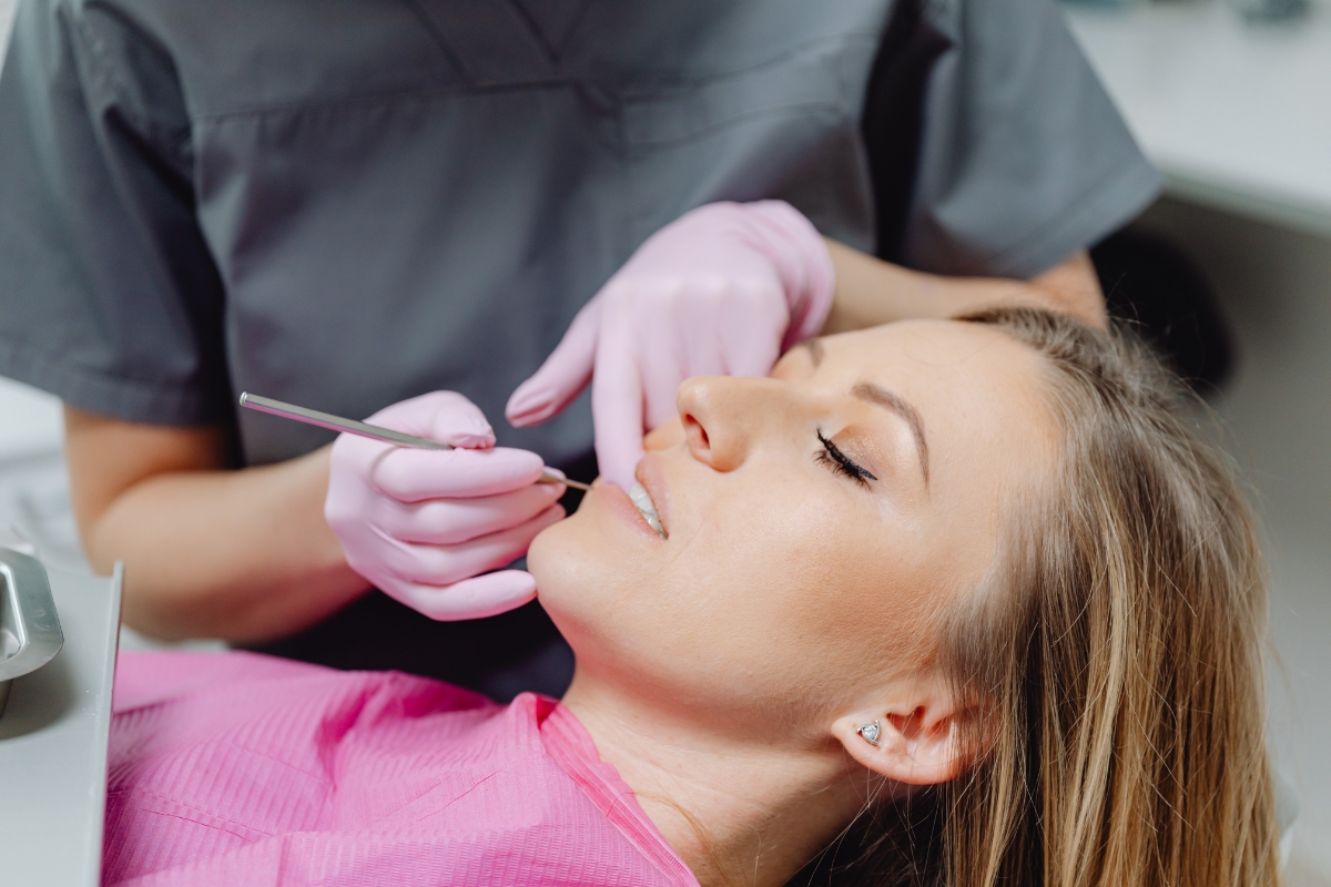 A dental professional treating a female patient in the dental chair at Aurora Dental Group