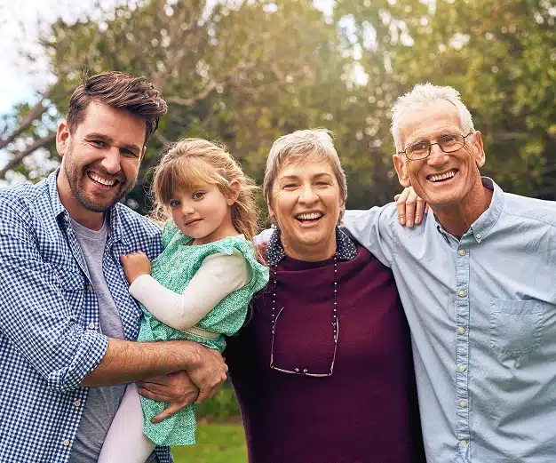 A happy multi generational family smiling together outdoors representing family dental care at Aurora Dental Group
