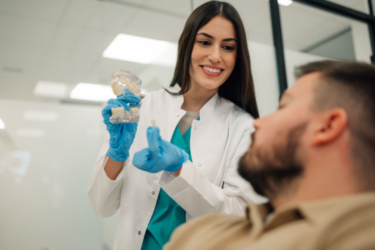 A dental professional in teal scrubs and gloves preparing for a dental procedure