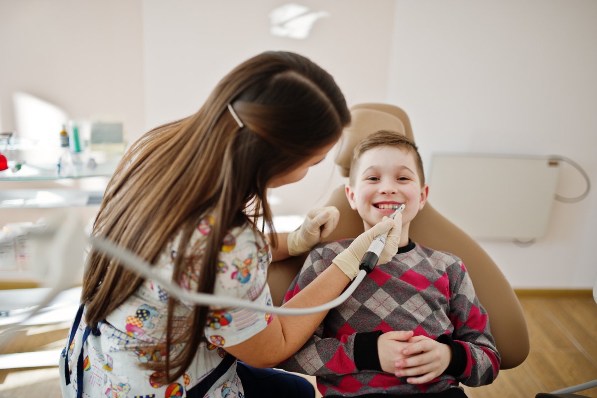 A dentist smiling with a young boy patient during a dental visit at Aurora Dental Group
