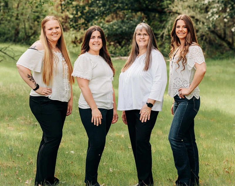 Four smiling women standing together outdoors in Grants Pass, Oregon.