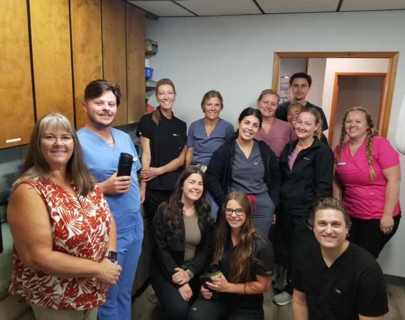 Dental practice team smiling together in office hallway at Grants Pass location.