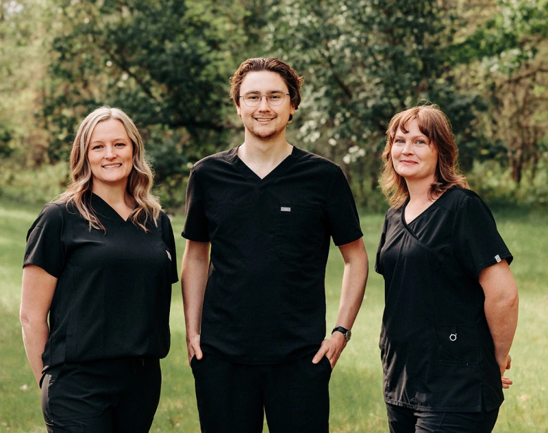 Three dental professionals smiling outdoors in Grants Pass, OR.