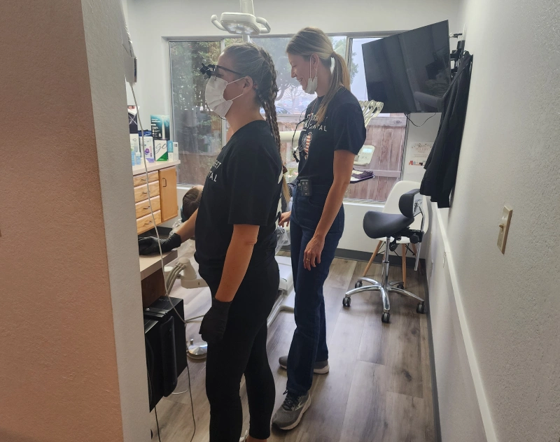 Two dental staff members in black scrubs consulting in a treatment room at Grants Pass dental office.