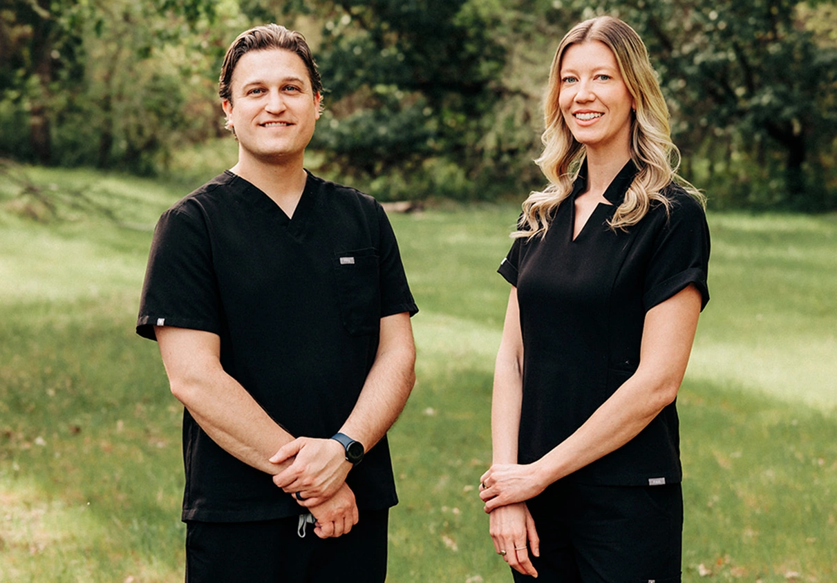 Two dental professionals in black scrubs standing outdoors in Grants Pass, OR.