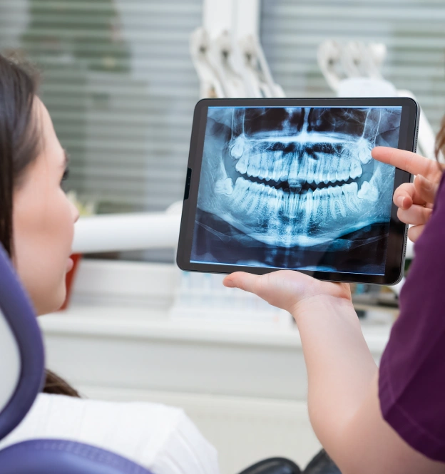 Dentist showing patient digital X-ray of teeth on tablet in Grants Pass office.