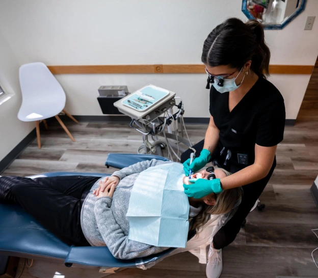 Dentist in teal gloves examining patient's teeth during emergency dental treatment in Grants Pass office.