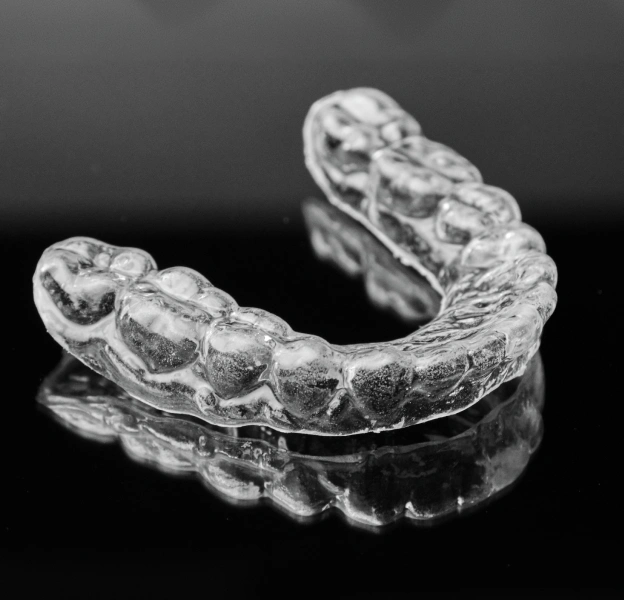 Clear dental night guards and mouth guards displayed on black background.