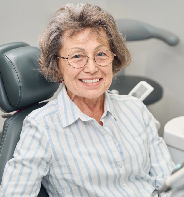 Smiling female dentist in blue striped shirt at Grants Pass periodontal care practice.