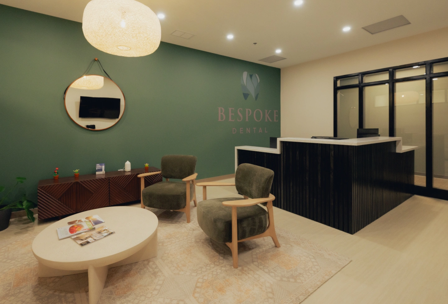 Modern dental practice waiting room with green accent wall, comfortable seating, and reception desk.