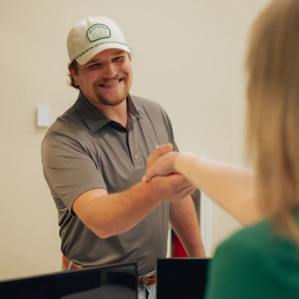 Smiling dentist in cap and polo shirt greeting patient at dental practice in Newnan, GA.