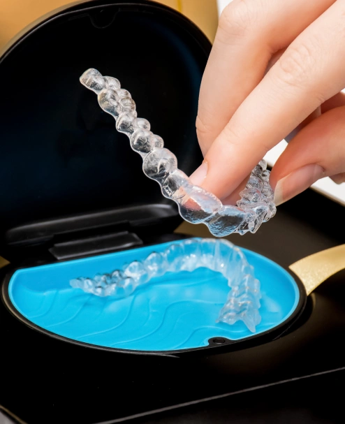 Clear Invisalign aligner being held above blue storage case at Newnan dental practice.