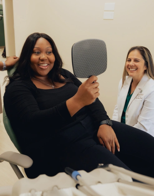 Patient examining smile results during Invisalign treatment consultation with dentist.