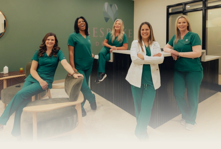 Five dental team members in teal scrubs posing together in a modern dental office in Newnan, GA.