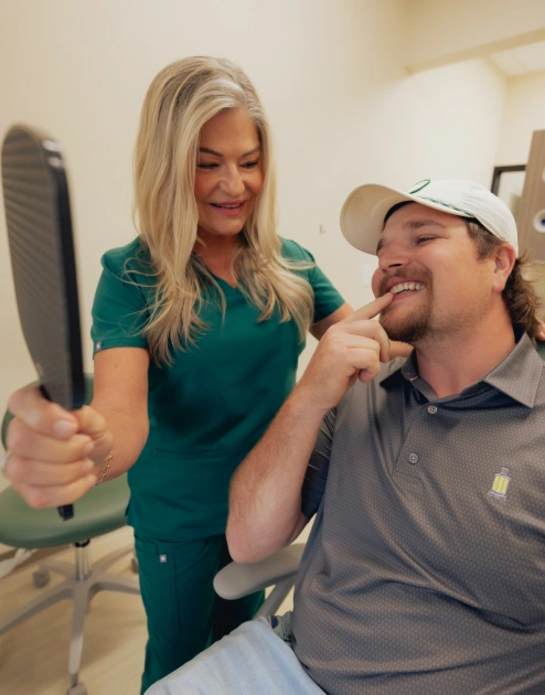 Dentist showing porcelain veneers smile results to happy patient in Newnan dental office.
