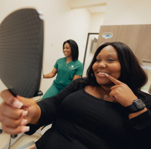 Patient smiling while holding Invisalign aligner tray at dental office in Newnan, GA.