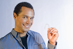 Man holding Invisalign aligner and smiling at Newnan dental practice.