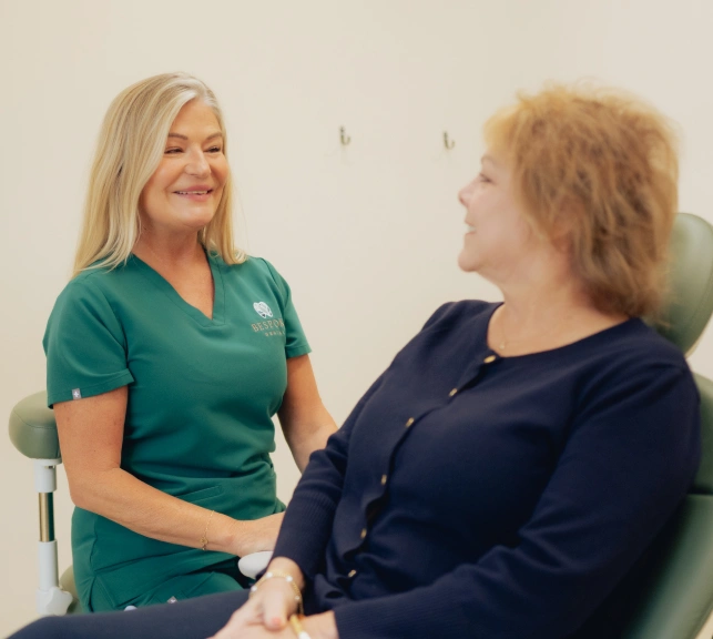 Female dentist in green scrubs smiling while consulting with patient in Newnan.
