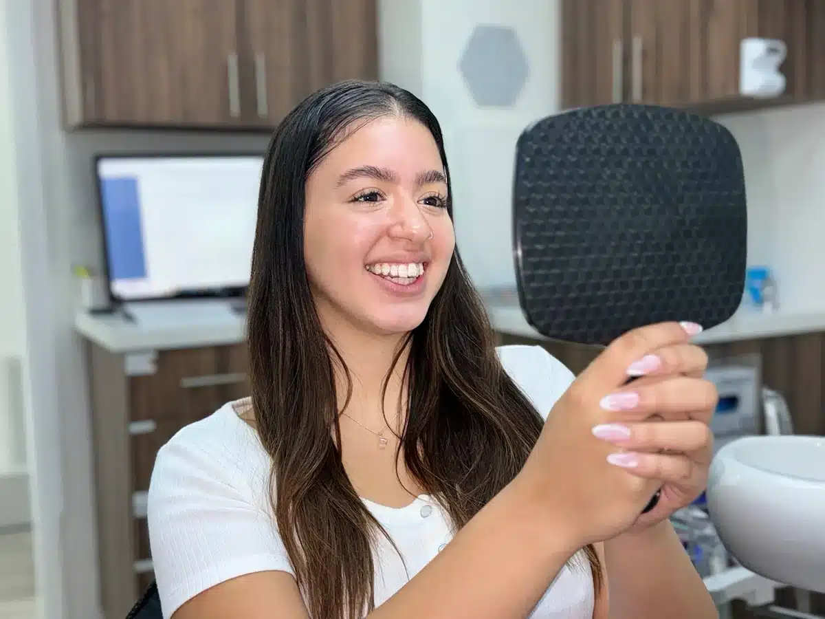 patient admiring improved smile after visiting Plantation dentist