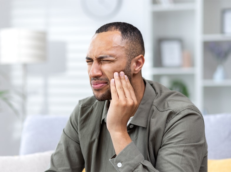 Man holding his cheek in pain, representing dental emergency symptoms.