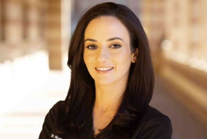 Smiling female dentist in black scrubs at Burbank dental practice.