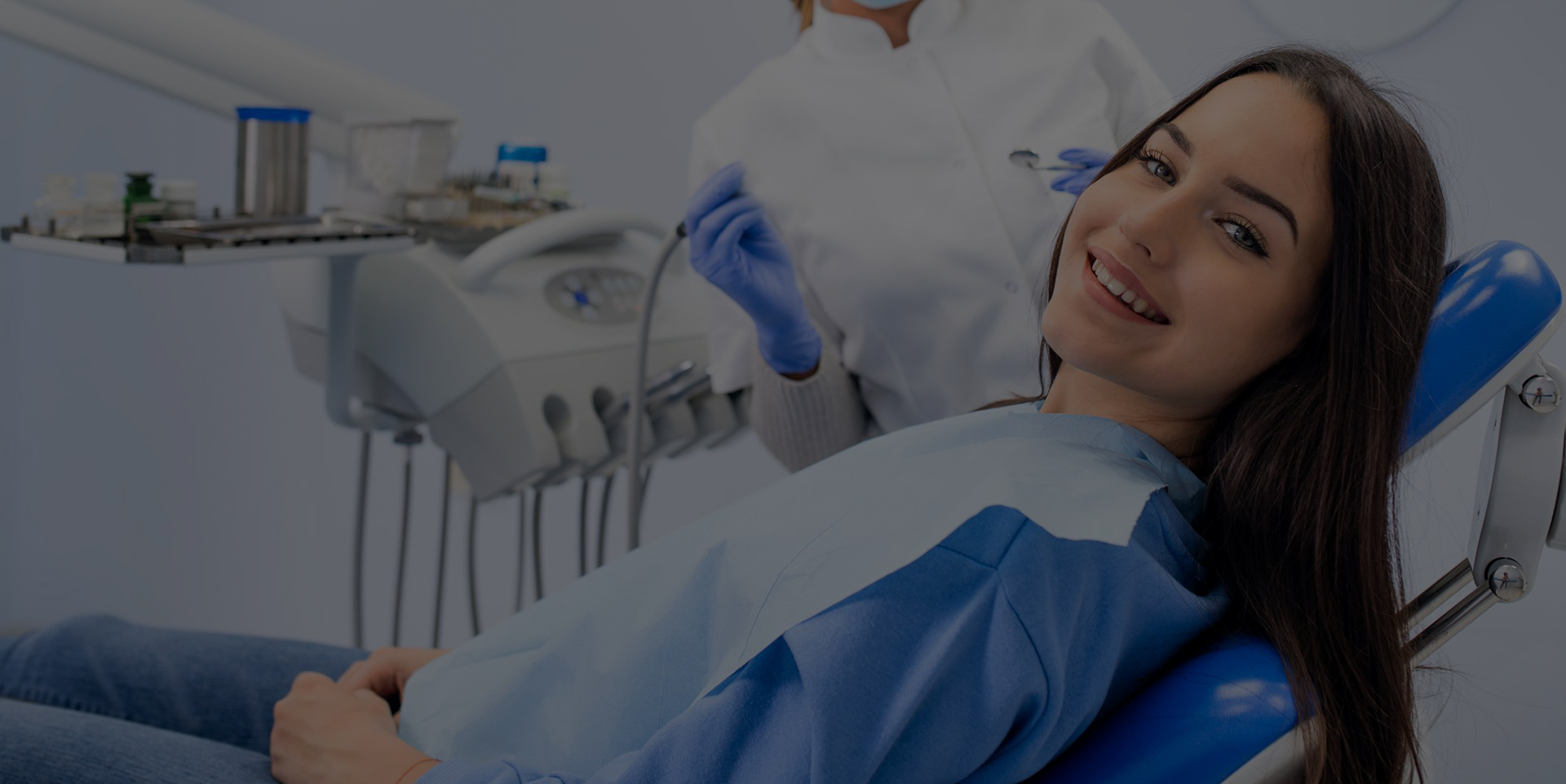 Dentist attends to a woman lying on a dental patient chair for oral surgery at Coastal Dental Arts in Peabody, MA.