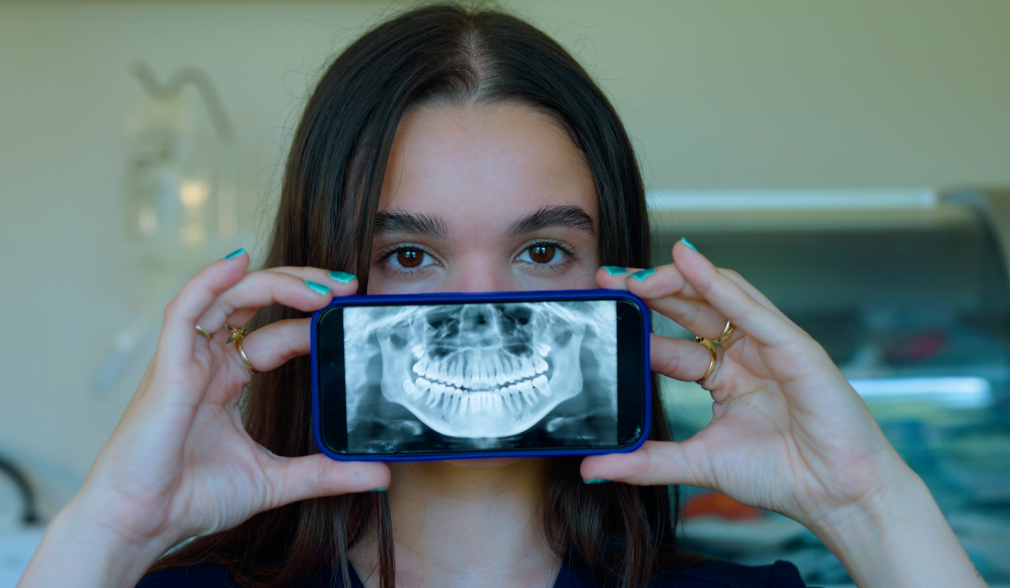 Woman holding a mobile phone displaying a dental 3D X-ray at Coastal Dental Arts in Peabody, MA