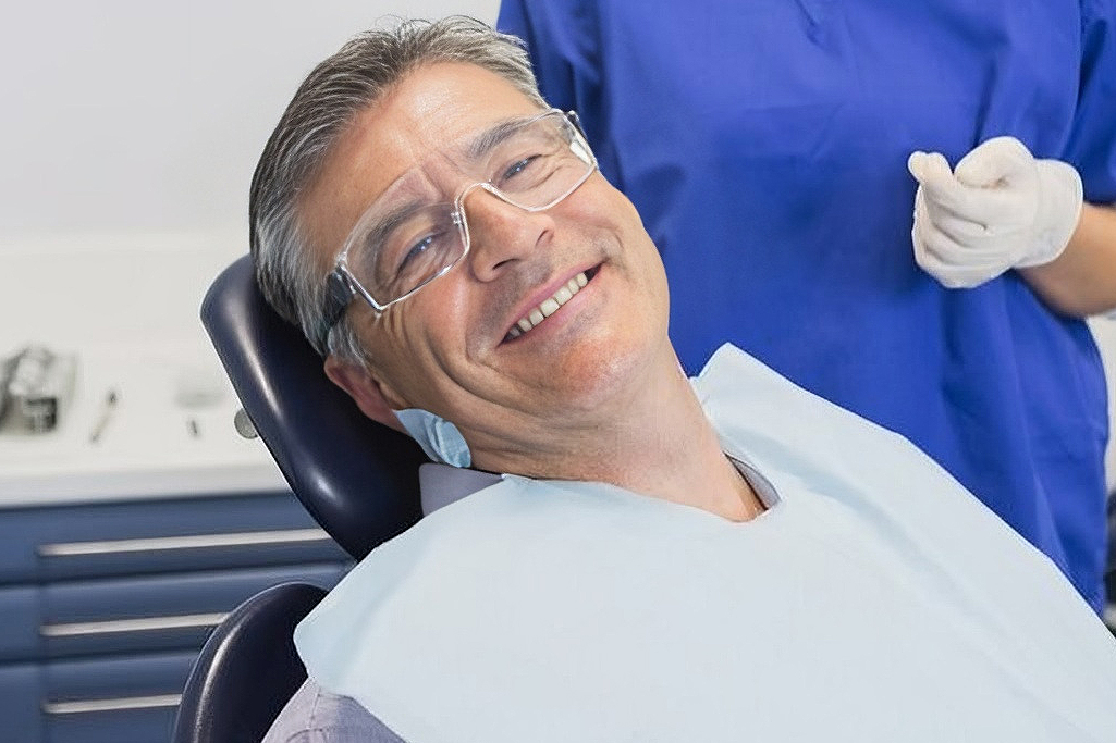 Elderly gentleman lying in a dental chair while being attended by a dentist for full mouth implant reconstruction at Coastal Dental Arts in Peabody, MA