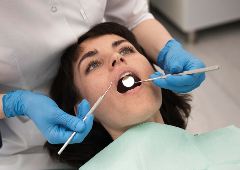 General dentist at Coastal Dental Arts in Peabody, MA checking a woman’s teeth while she lies in a dental chair