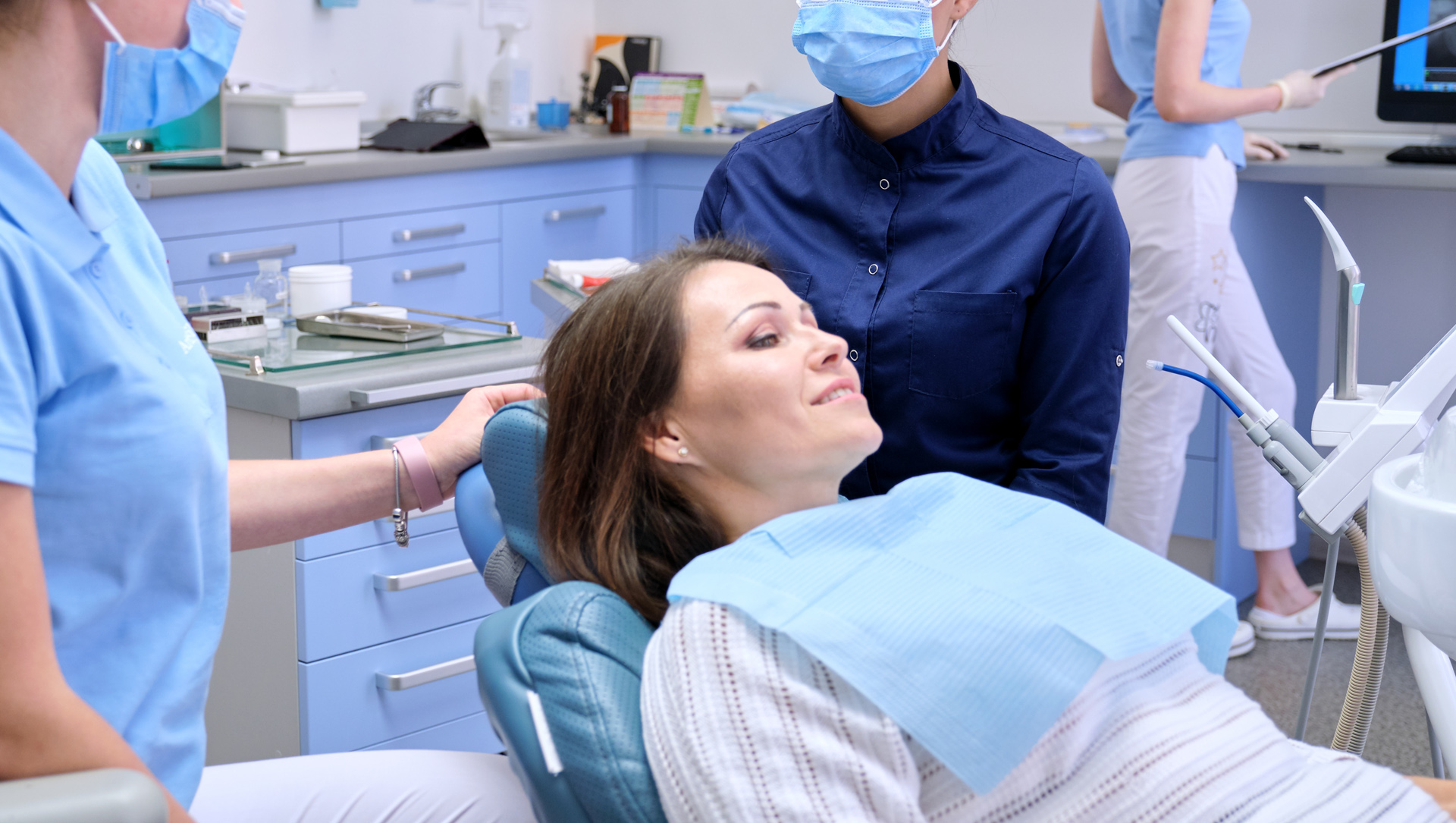 Woman lying in a dental treatment chair receiving IV sedation with a dentist and assistant beside her at Coastal Dental Arts in Peabody, MA