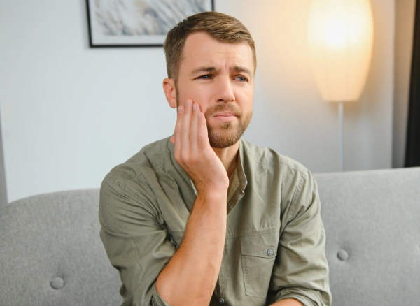Man holding his jaw while experiencing a dental emergency due to severe tooth pain