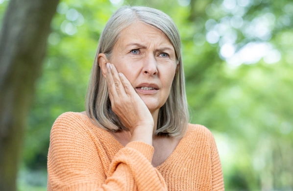 Woman experiencing tooth pain before a gentle tooth extraction procedure