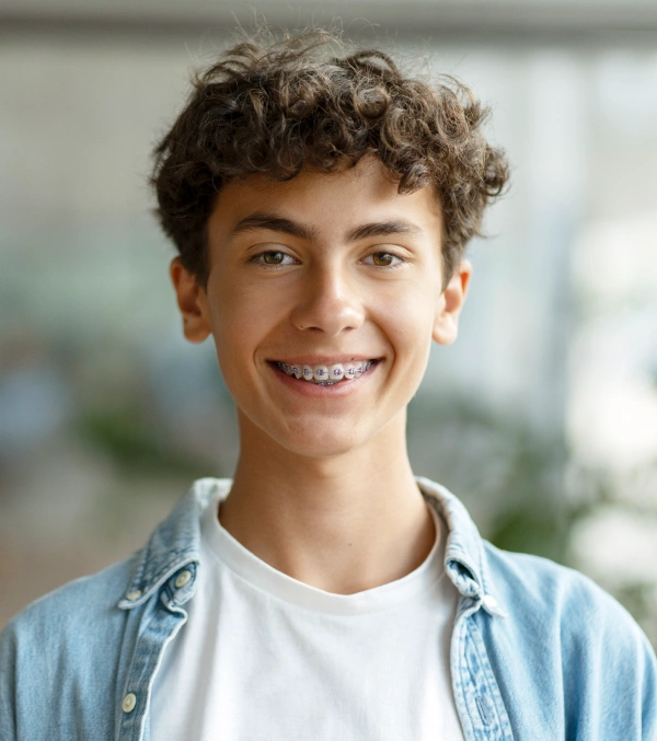 Teen smiling with traditional metal braces after orthodontic treatment consultation