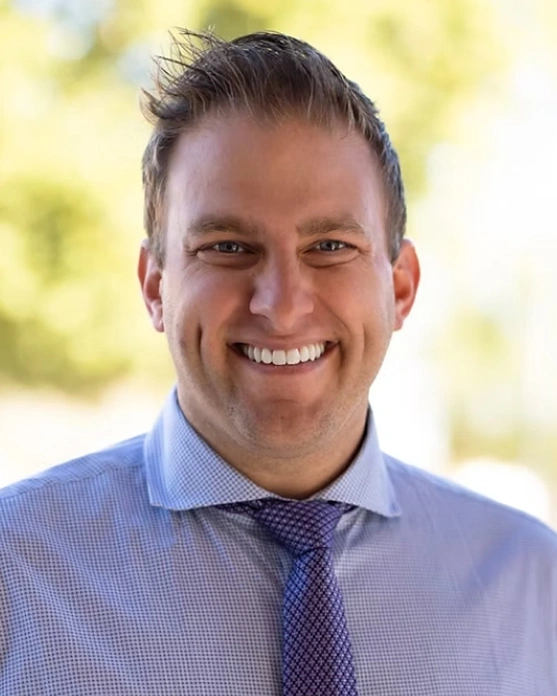 Dr. Alex Wardian, Lead Dentist at Clear Sky Dental Care, smiling in a blue shirt and purple tie.
