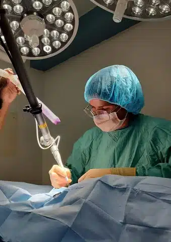 Veterinarian performing laser surgery under surgical lights