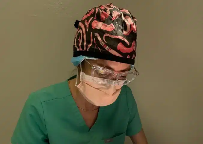 Veterinary surgeon in scrubs, mask, and protective eyewear
