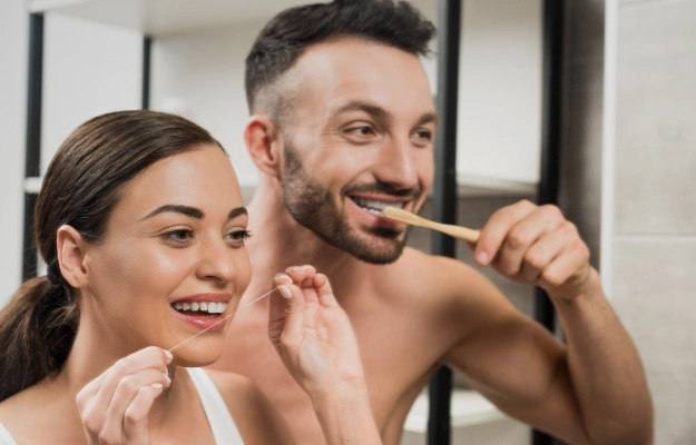 Couple brushing their teeth together as part of a healthy oral hygiene routine