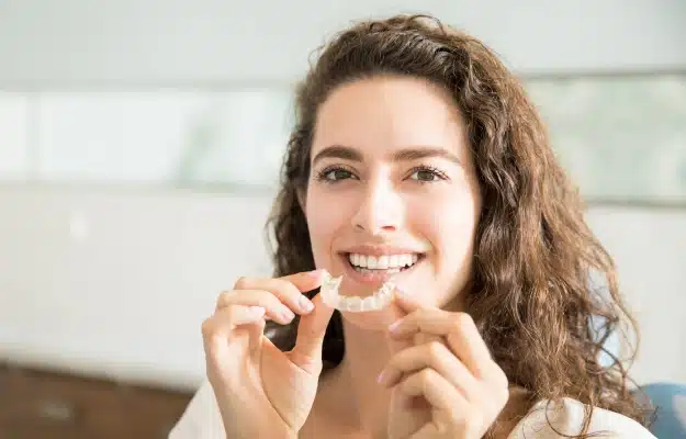 Woman inserting a clear aligner during orthodontic treatment