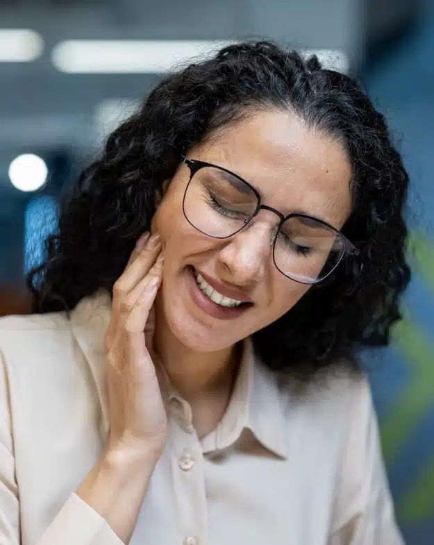 Woman holding her jaw due to tooth pain and sensitivity