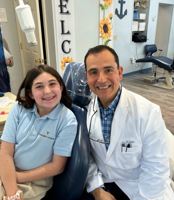 Dr. Cosmo Haralambidis smiling with a patient inside Cranston Orthodontics