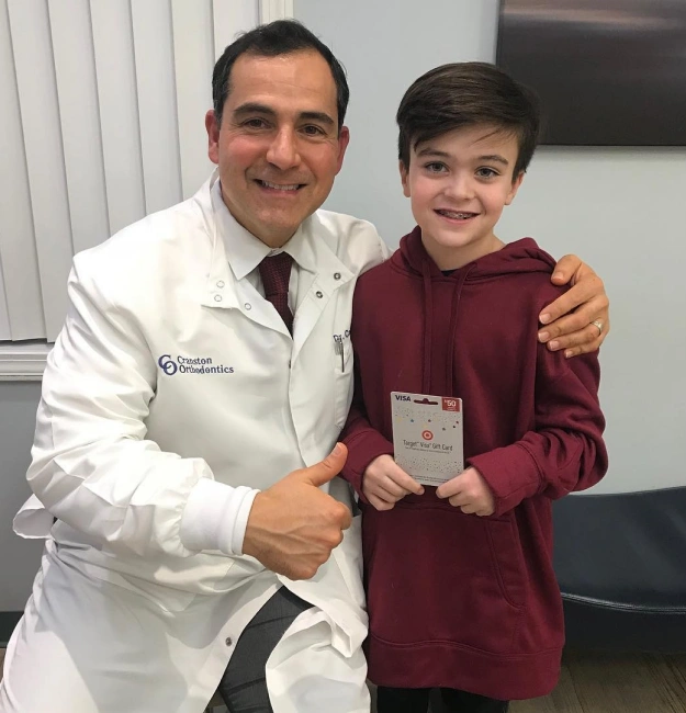 Dr. Cosmo Haralambidis posing with a young patient at Cranston Orthodontics