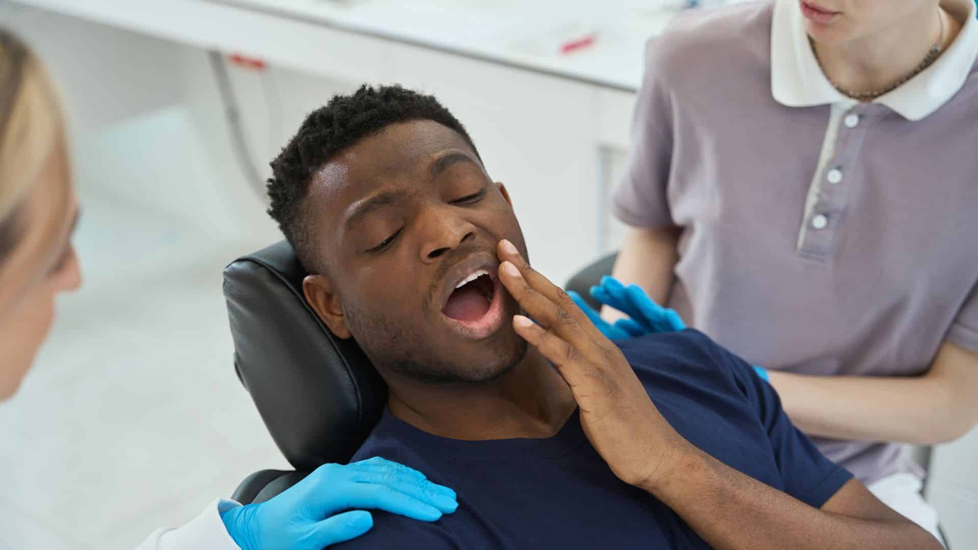 a black men seating on dentist chair with tooth pain and ready to take emergency dental care in Culver City CA