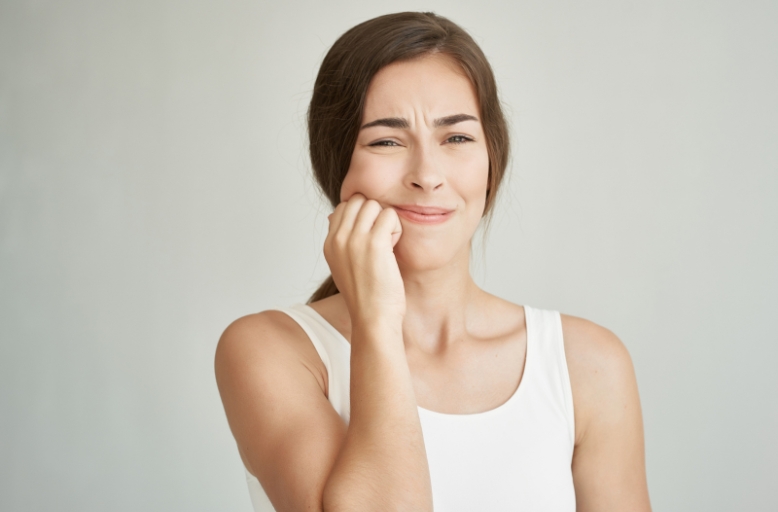 Woman experiencing severe tooth pain seeking emergency dental care in South Austin, TX.