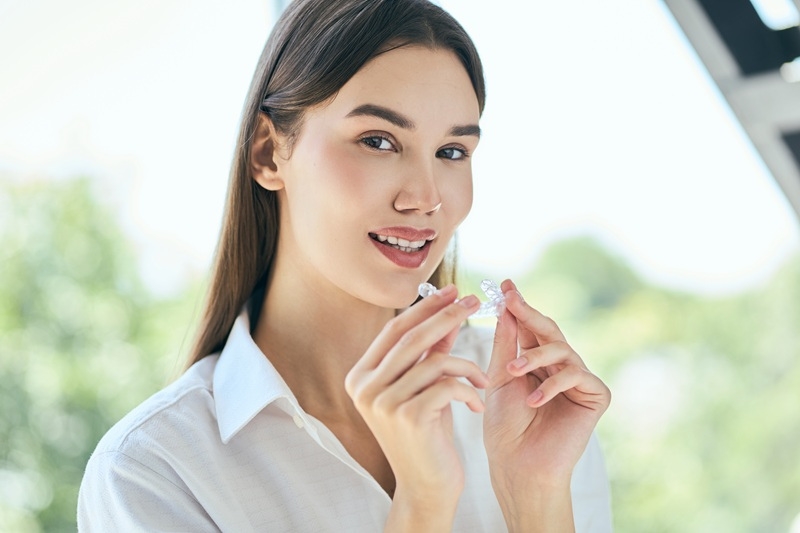 Young woman holding Invisalign clear aligners during a cosmetic dental consultation at Daylight Dental South Austin.