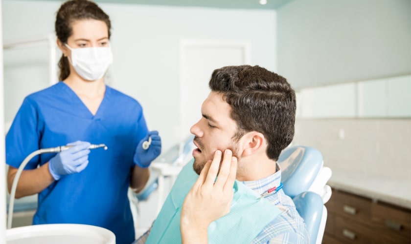 Female dentist examining a young male patient's teeth in a dental office