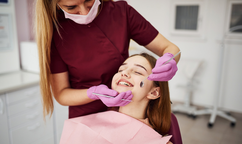 Dentist in a mask checking teeth of a patient